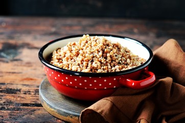 Boiled buckwheat with butter in a pan on a dark wooden background