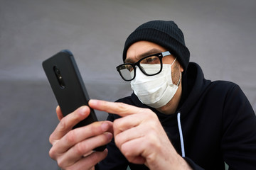 Coronavirus. A man in a protective mask with a phone in his hands. Covid 19. Pandemic 20.