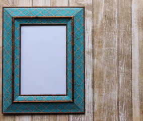 Fototapeta premium A photograph of a decorative turquoise picture frame against a wood effect background. Blank interior of the frame for your own text. Copy space. Perfect advertising or pricing frame. 
