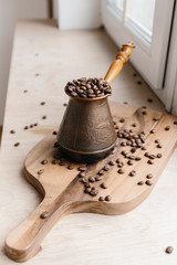 Turkish coffee pot full of coffee beans on wooden board