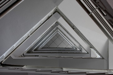 Fototapeta premium A photograph looking upwards in a stairwell, triangle geometric shape pattern. Internal building architecture