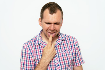 Fototapeta premium male of European appearance causes vomiting putting his fingers in his mouth on a gray background, nausea