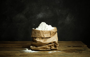 Flour for baking pizza dough, bread and pasta on a wooden table and dark background. Home cooking concept