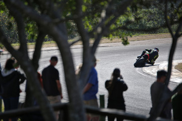 Racing Motorcycle leaning into a fast corner on race track with spectators in the foreground.