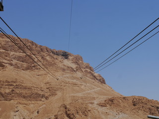 cable car leading to top of the mountain of famous Masada Fortress with snail hiking trail in the back, near Negev Desert near Ein Gedi, Israel