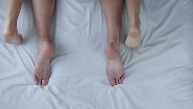Loving couple having sex. Male and female legs in bed. Couple in bed making petting and love. Top view. Marriage, family, love, sex concept.