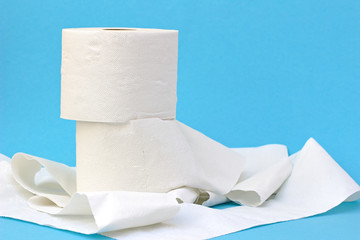 Toilet paper on light blue background. Toilet paper crisis because of Corona. Bottleneck.