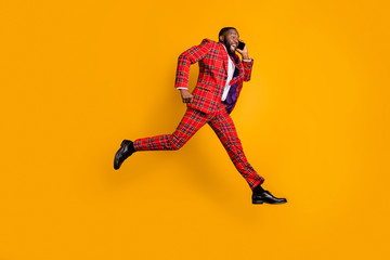 Fototapeta na wymiar Discounts i hurrry. Full size profile side photo crazy funky dark skin guy pause break jump up use cellphone tell say run runner wear red plaid pants tie tuxedo isolated yellow color background