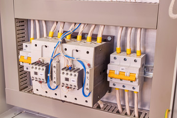 Two power contactors with front additional contacts and two circuit breakers in the electrical Cabinet. Cables and wires are connected to magnetic starters and switches according to the project.