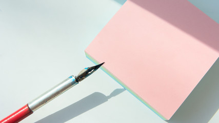 tear-off block for notes on a white background. Sunlight. To the left of the block lies a fountain pen. Copy space