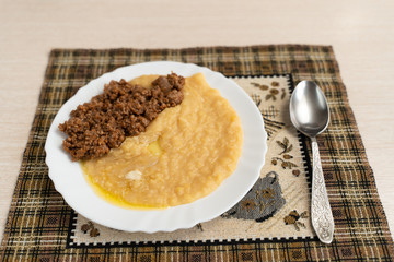 Yellow pea puree with meat in a white plate