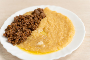 Yellow pea puree with meat in a white plate