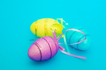 Three Easter toy eggs on a blue background.