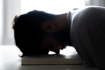 Student tired of studying sleeping with his head on a book