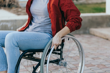 Close up of a young woman in a wheelchair while walking in a park on a sunny day. Recovery and...