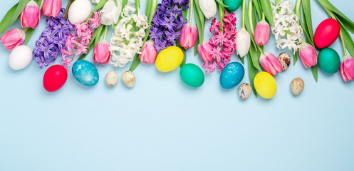 Easter composition. Multicolored easter eggs, tulips and hyacinths on blue background. Easter concept. Copy space