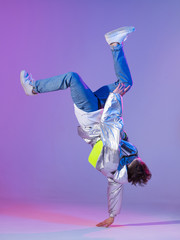 Cool guy dancing contemporary dance in studio. Neon light background. Acrobatic bboy dancer. Break dance lessons. - obrazy, fototapety, plakaty