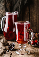 Fruit compote of berries in a glass on rustic wooden table with a jug. Summer drink