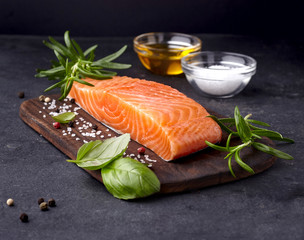 Salmon fish on the stone with fresh  rosemary, basil  and spices.  Steak on black background.