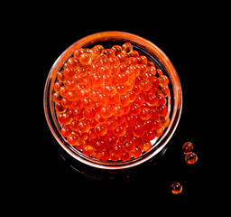 Caviar in glass bowl on black background top view