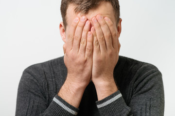  man covers his face by hand