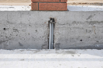 Corrugated conduit pipe for electrical wiring protection cemented in the fence foundation for...