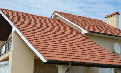 Red double gable roof covered with ceramic, clay roof tiles with chimney, brown roof gutter and a...