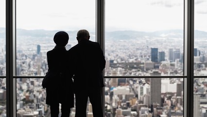 Portrait silhouette from behind view of old senior couple looking beautiful view of urban cityscape...
