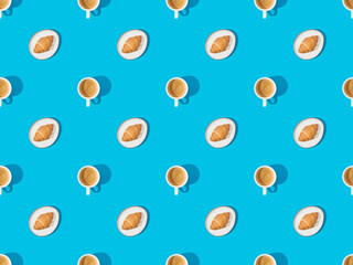 top view of croissants on plates and coffee on blue, seamless background pattern