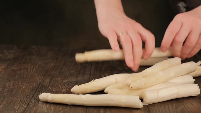 Woman breaks a stick of raw white asparagus. Healthy food.