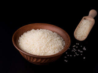 Fototapeta na wymiar rice in a clay bowl on a black background