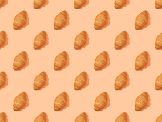 top view of fresh croissants on orange, seamless background pattern