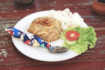 Fried rice with some crackers, tomato, and lettuce, plated on classic wood table
