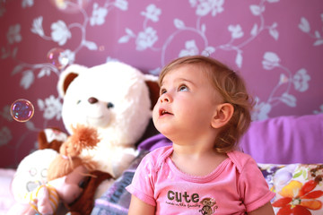little cute caucasian girl plays in her room with soap bubbles. Children's emotions, smile and laughter. Close-up.