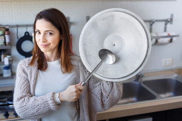 bella ragazza gioca con un coperchio di una pentola e un mestolo 