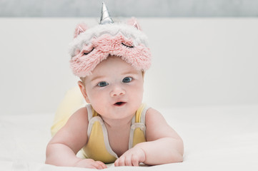 Portrait of a baby in a mask for sleeping on his head in the form of a unicorn. cute infant.