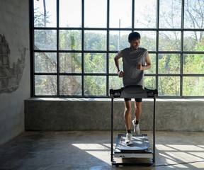 Obraz na płótnie Canvas Young man in sportswear running on treadmill at gym