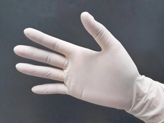 Female hands with disposable latex gloves wearing gesture, selective focus.