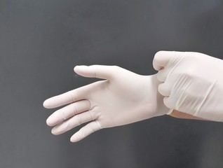 Female hands with disposable latex gloves wearing gesture, selective focus.