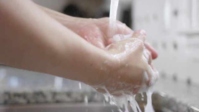 Washing hands in kitchen sink under running water 120fps
