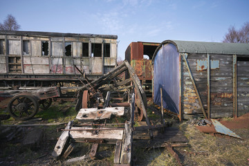 Abandoned train depot with various trains and carriages in different states of decay.