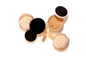 Face loose makeup powder. Real cosmetic powder in the black round glossy plastic case cover Isolated on white background and harsh shadows. Top view.