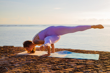 Female practicing variation Mayurasana, Peacock pose. Hand-balancing asana in hatha yoga. Strong...