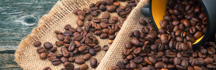 Roasted coffee beans on jute. Coffee bean mug. Panorama.