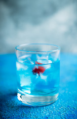 Blue old fashioned cocktail with cherry on the rustic background. Selective focus. Shallow depth of field.