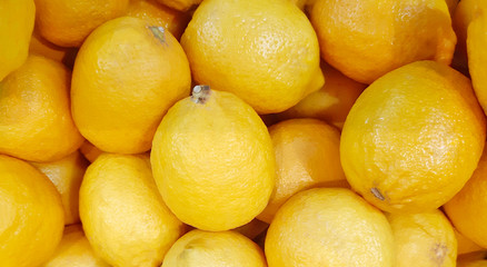 A lot of fresh yellow lemons on market display. Close up fruit background for healthy food concept.
