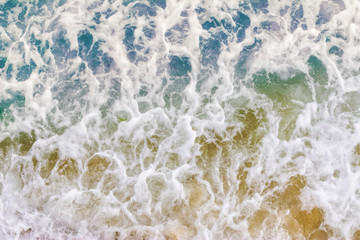 Top view texture waves, foaming and splashing in the ocean, sunny day.  Beautiful tropical sea in summer season image by aerial view. Abstract sea background. Ocean waves close-up.
