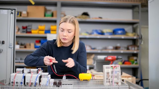 Female electrician using voltmeter and checking voltage