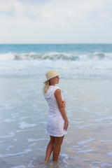Fototapeta na wymiar Portrait of woman walking on the beach looking at the sea. Relaxed lady strolling on the beach.