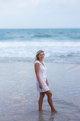 Portrait of woman walking on the beach looking at the sea. Relaxed lady strolling on the beach.